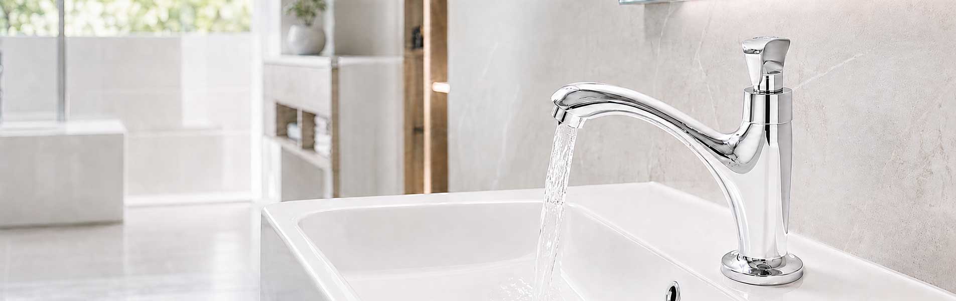 Vòi lavabo lạnh sáng bóng đang xả nước vào chậu rửa bằng đá